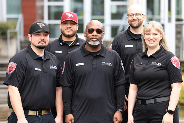 uniformed campus safety officers stand in front of cascade building on fort steilacoom campus