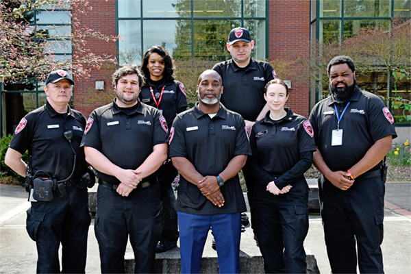 uniformed campus safety officers stand in front of college center building on the puyallup campus