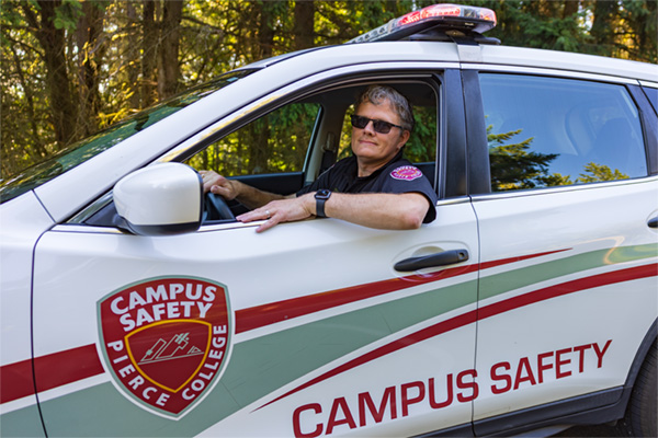 campus safety officer wearing sunglasses while driving car with campus safety logo on the side