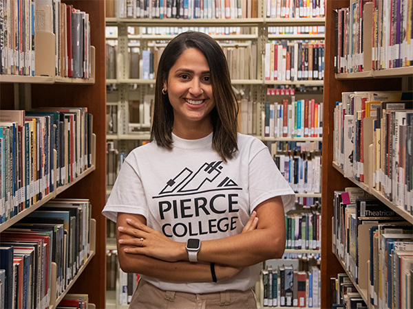smiling student with arms crossed in library