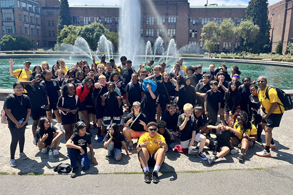 large group of students pose outside in front of fountain