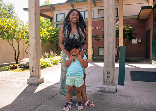 student and her child embrace outside the child development center