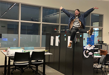 cheering student in computer lap sitting on top of filing cabinets