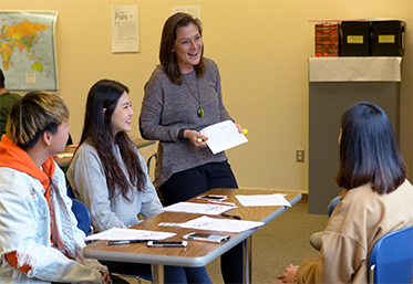 teacher speaking to small group of students in classroom