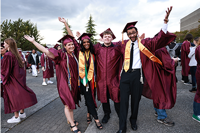 Pierce College graduates pose at the Tacoma Dome in red robes with gold stoles