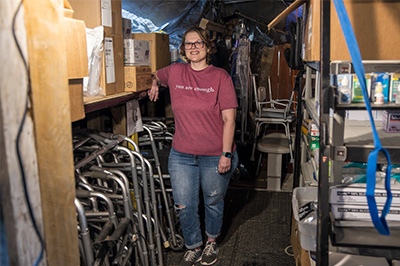 Shatone Martin stands in the packed storage center for Helping Hands LLC in front of a row of mobility assistant devices