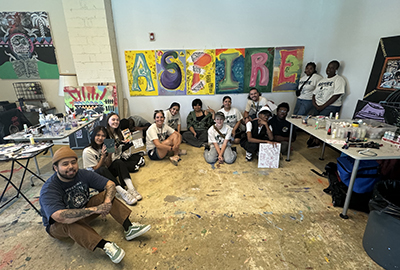 Students sitting below large painting of the word ASPIRE