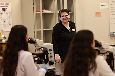 Markiva Contris stands in classroom with students working at microsopes