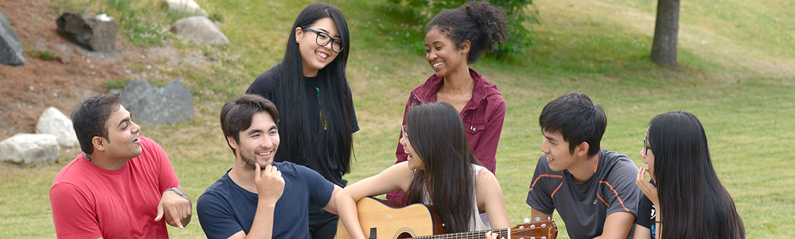 group of students sitting outside with guitar