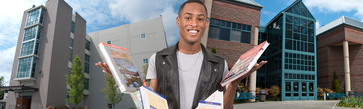 smiling student standing in front of jblm buildings dropping textbooks