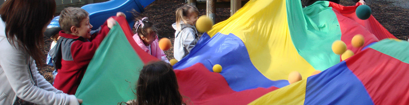 adult and children playing with a large canvas and balls