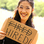 person holding sign that has the word fired crossed out and the word hired replacing it